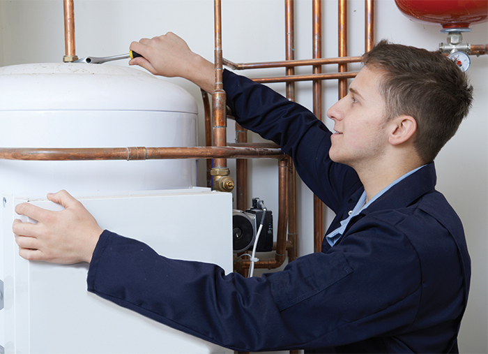 Male Plumber Working On Central Heating Boiler